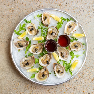 Circular tray of oysters with sauces and lemon from Katie's Pizza & Pasta Osteria.
