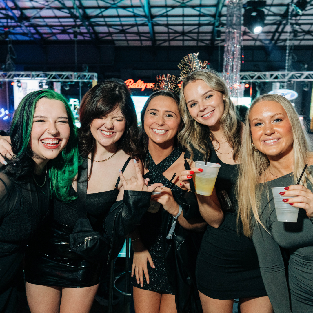 Group of friends smiling for camera with drinks at New Year's Eve celebration