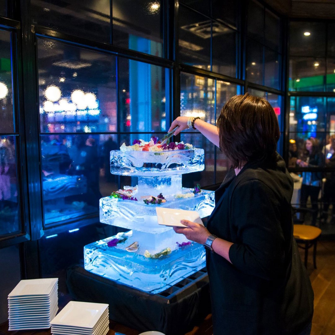 Woman getting food from a tiered serving platter at New Year's Eve party.